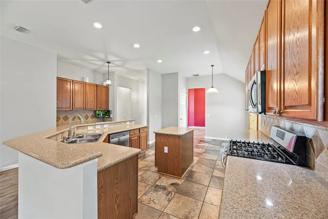a kitchen with stainless steel appliances granite countertop a sink and a refrigerator
