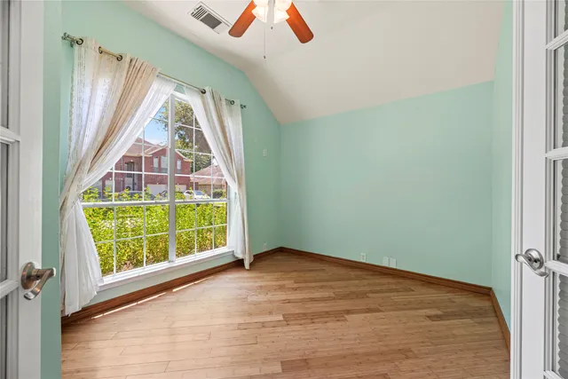an empty room with wooden floor and windows