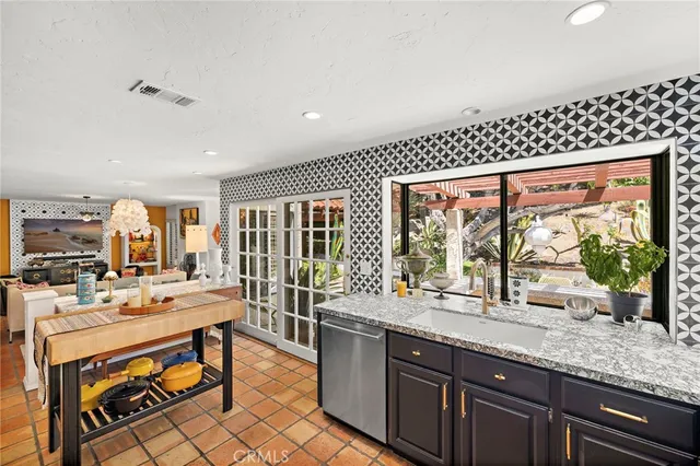 a room with stainless steel appliances kitchen island granite countertop a sink and cabinets