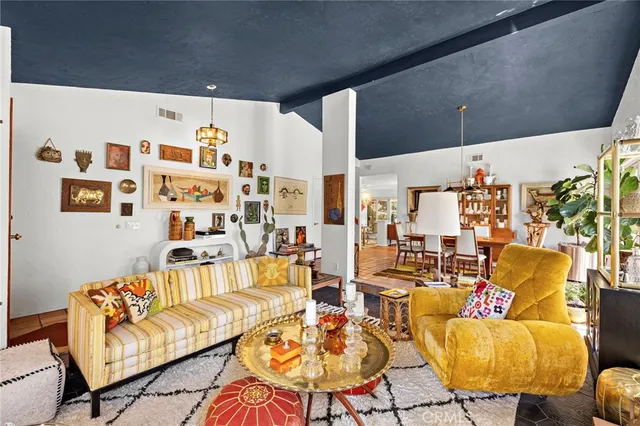 a living room with couches and kitchen view with wooden floor