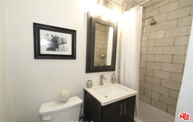 a bathroom with a toilet a sink a mirror and a shower