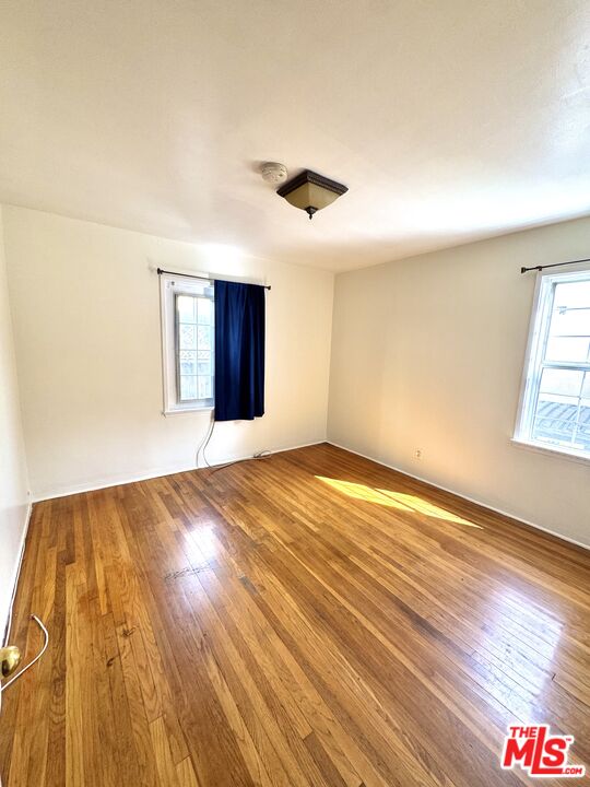 11926 West Magnolia Boulevard, Unit 1/4 Valley Village, CA 91607 - Photo 6 of 12 an empty room with wooden floor and windows