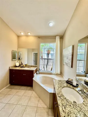 a large bathroom with a granite countertop tub sink and mirror
