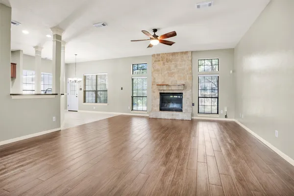 a view of a hallway with wooden floor and chandelier fan