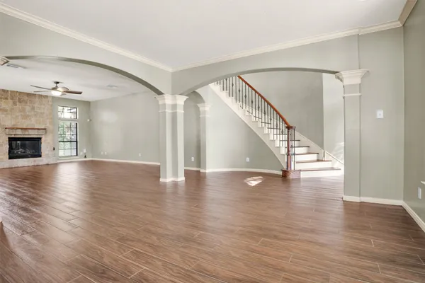 an empty room with wooden floor chandelier and windows