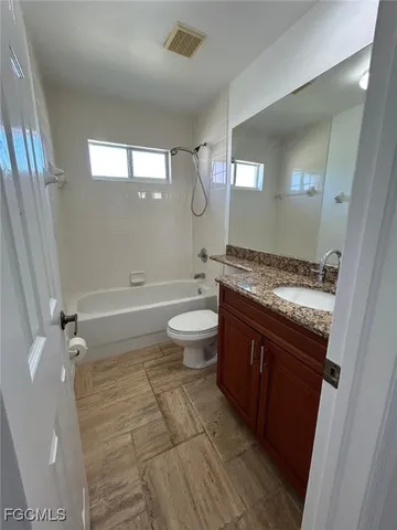 a bathroom with a granite countertop toilet a sink and a mirror