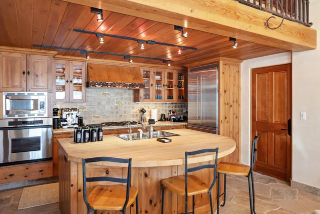 a kitchen with stainless steel appliances kitchen island granite countertop a table chairs in it and wooden floors