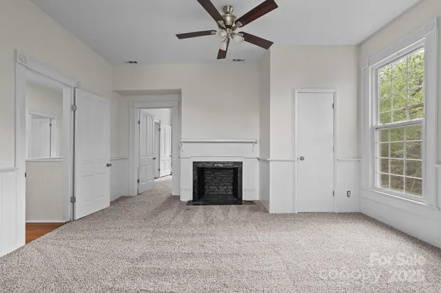 an empty room with windows and fireplace