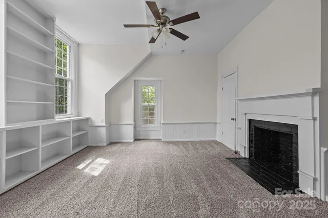 an empty room with windows and fireplace