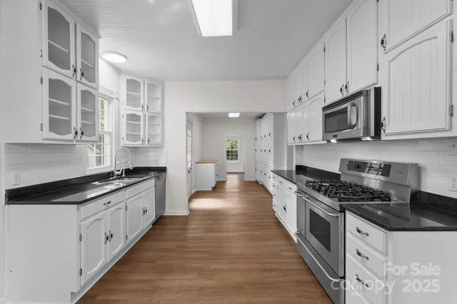 a large kitchen with stainless steel appliances granite countertop a stove and a white cabinets