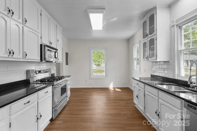a kitchen with stainless steel appliances a stove cabinets and wooden floor