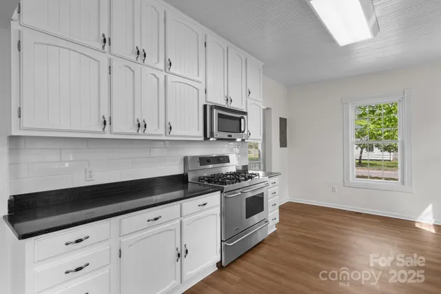 a kitchen with granite countertop white cabinets and appliances