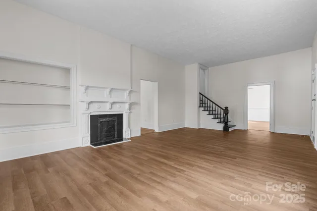 a view of empty room with wooden floor and fireplace