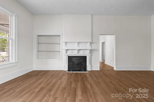 a view of empty room with wooden floor and fireplace