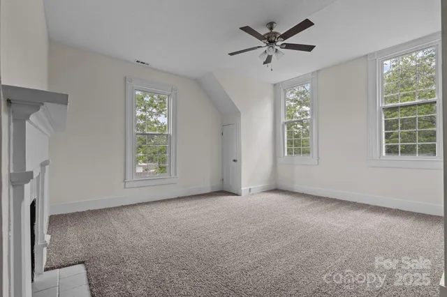an empty room with windows and chandelier fan