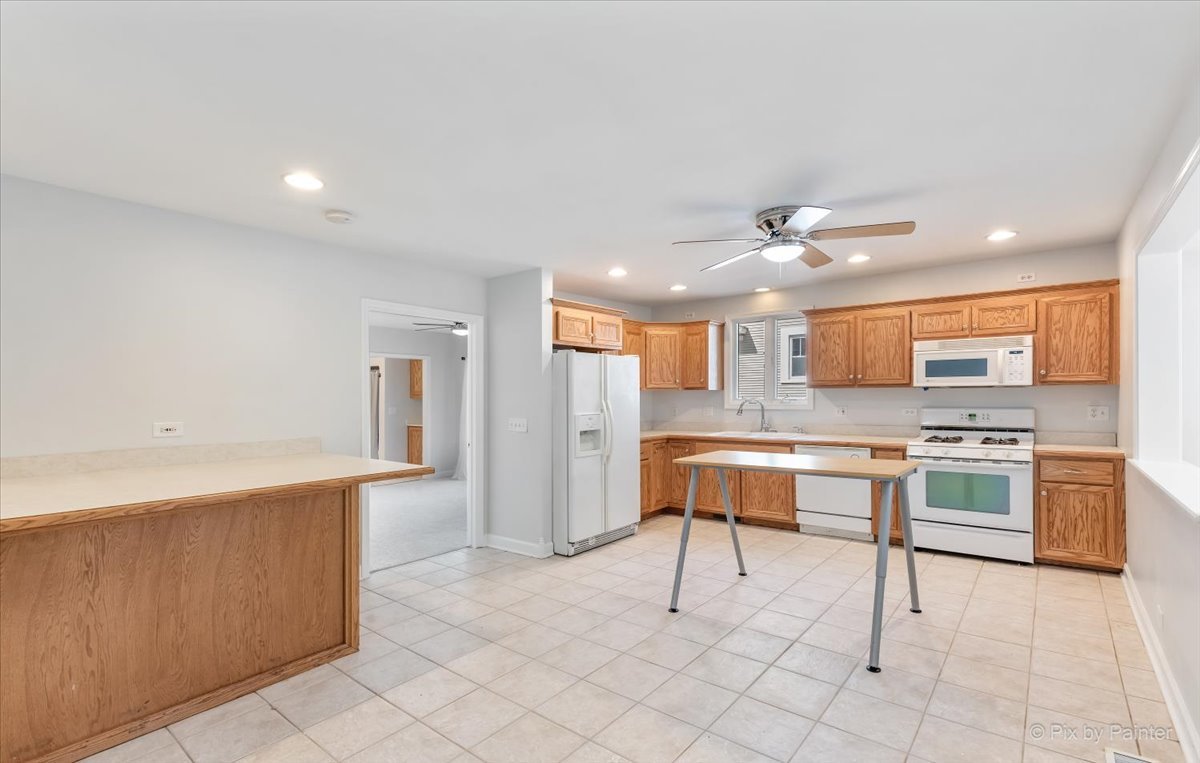 30 Crissey Avenue Geneva, IL 60134 - Photo 13 of 48 a large white kitchen with a stove a sink dishwasher and a refrigerator with wooden floor