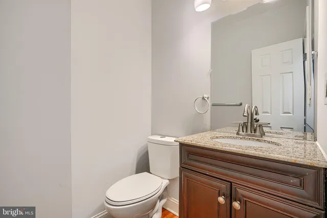 a bathroom with a granite countertop toilet sink and mirror