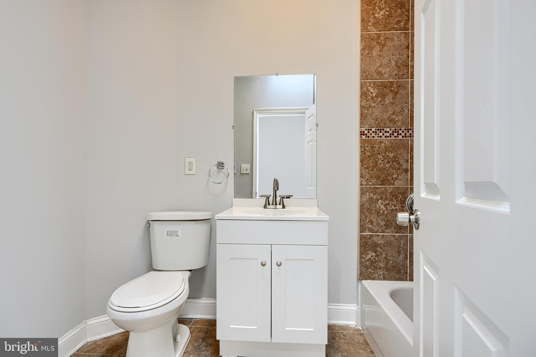 2511 McCulloh Street Baltimore, MD 21217 - Photo 21 of 35 a bathroom with a granite countertop toilet a sink and a mirror