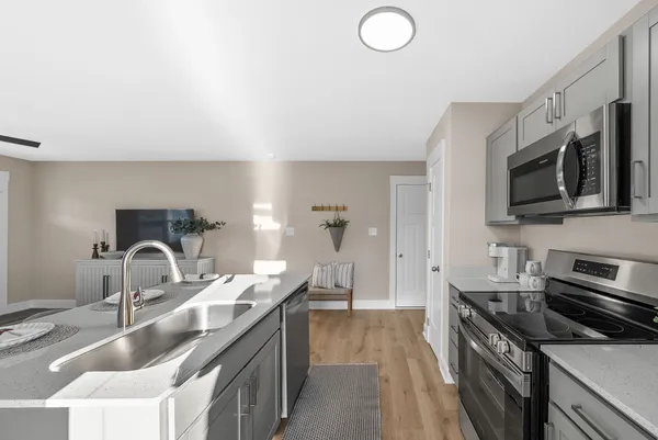 a kitchen with granite countertop a sink and a stove top oven with wooden floor