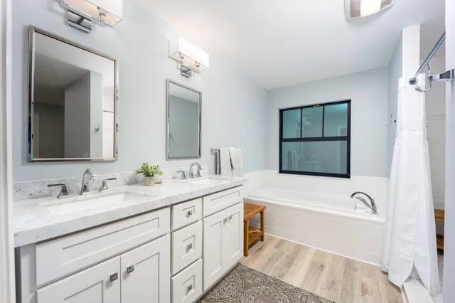 a bathroom with a tub a sink and mirror