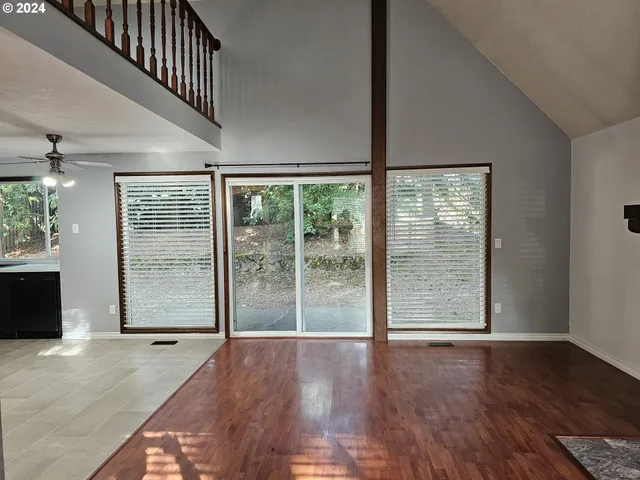 a view of an empty room with wooden floor and windows