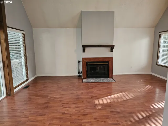 a view of empty room with wooden floor and fireplace