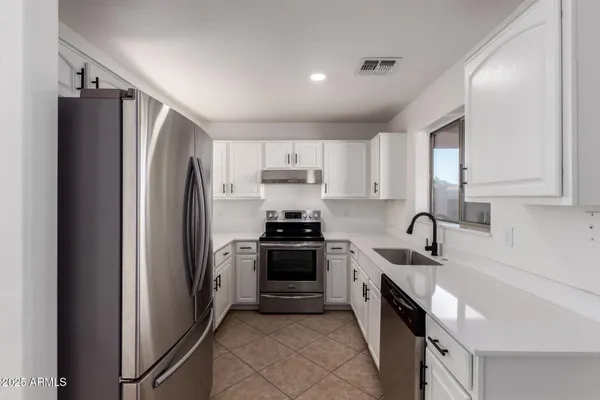 a kitchen with stainless steel appliances granite countertop a refrigerator sink and stove