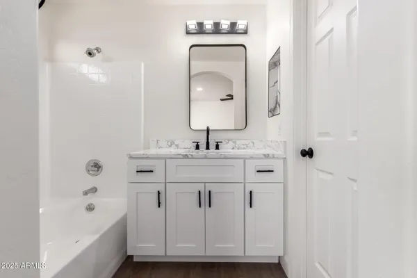 a bathroom with a double vanity sink mirror and bathtub