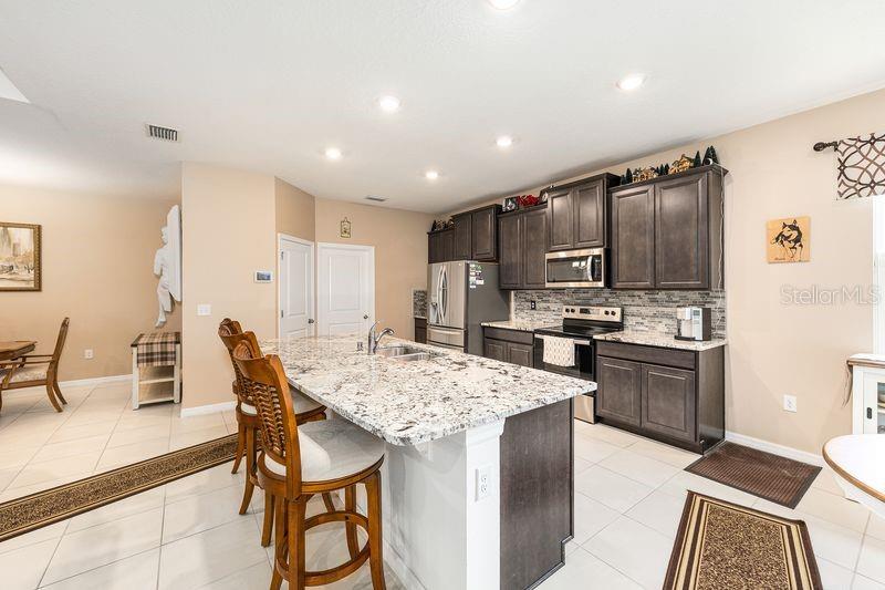 5077 Northeast 16th Street Ocala, FL 34470 - Photo 16 of 47 a kitchen with granite countertop kitchen island stainless steel appliances a stove a table and chairs