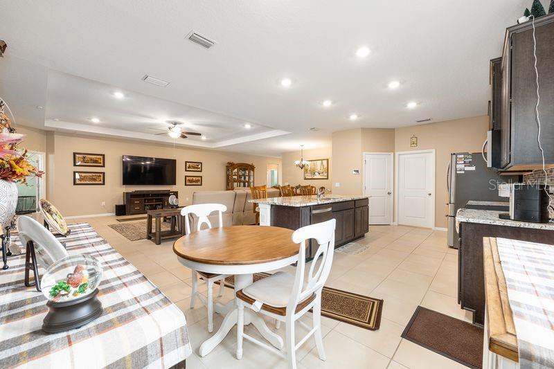 5077 Northeast 16th Street Ocala, FL 34470 - Photo 17 of 47 a kitchen with stainless steel appliances kitchen island granite countertop a refrigerator a stove a sink dishwasher and a dining table with wooden floor