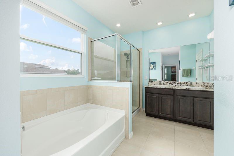 5077 Northeast 16th Street Ocala, FL 34470 - Photo 25 of 47 a bathroom with a bathtub a double vanity sink and a large mirror