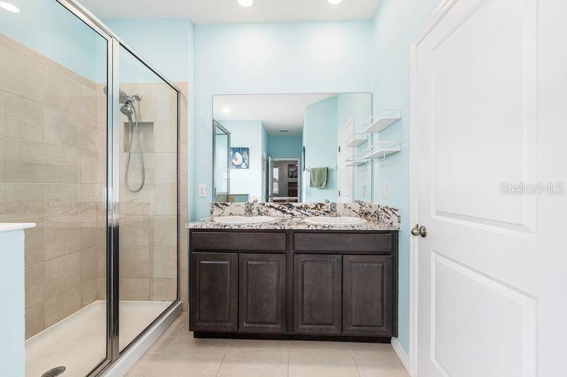 5077 Northeast 16th Street Ocala, FL 34470 - Photo 26 of 47 a bathroom with a granite countertop sink a mirror and a shower