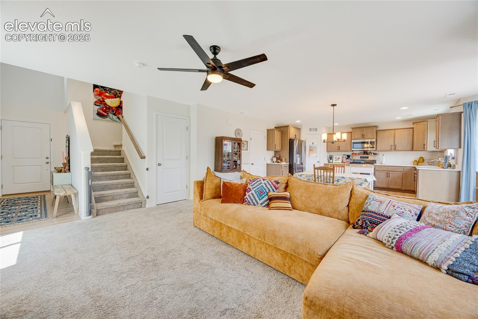 Open-concept living space featuring light carpeting and a contemporary ceiling fan