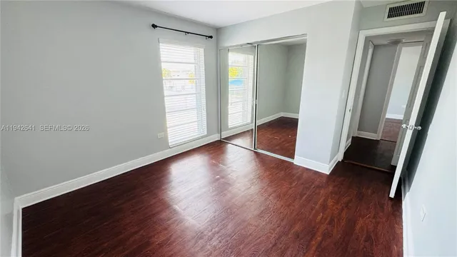 an empty room with wooden floor and window