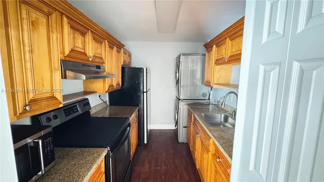 a kitchen with stainless steel appliances granite countertop a refrigerator a stove and a sink with wooden floor