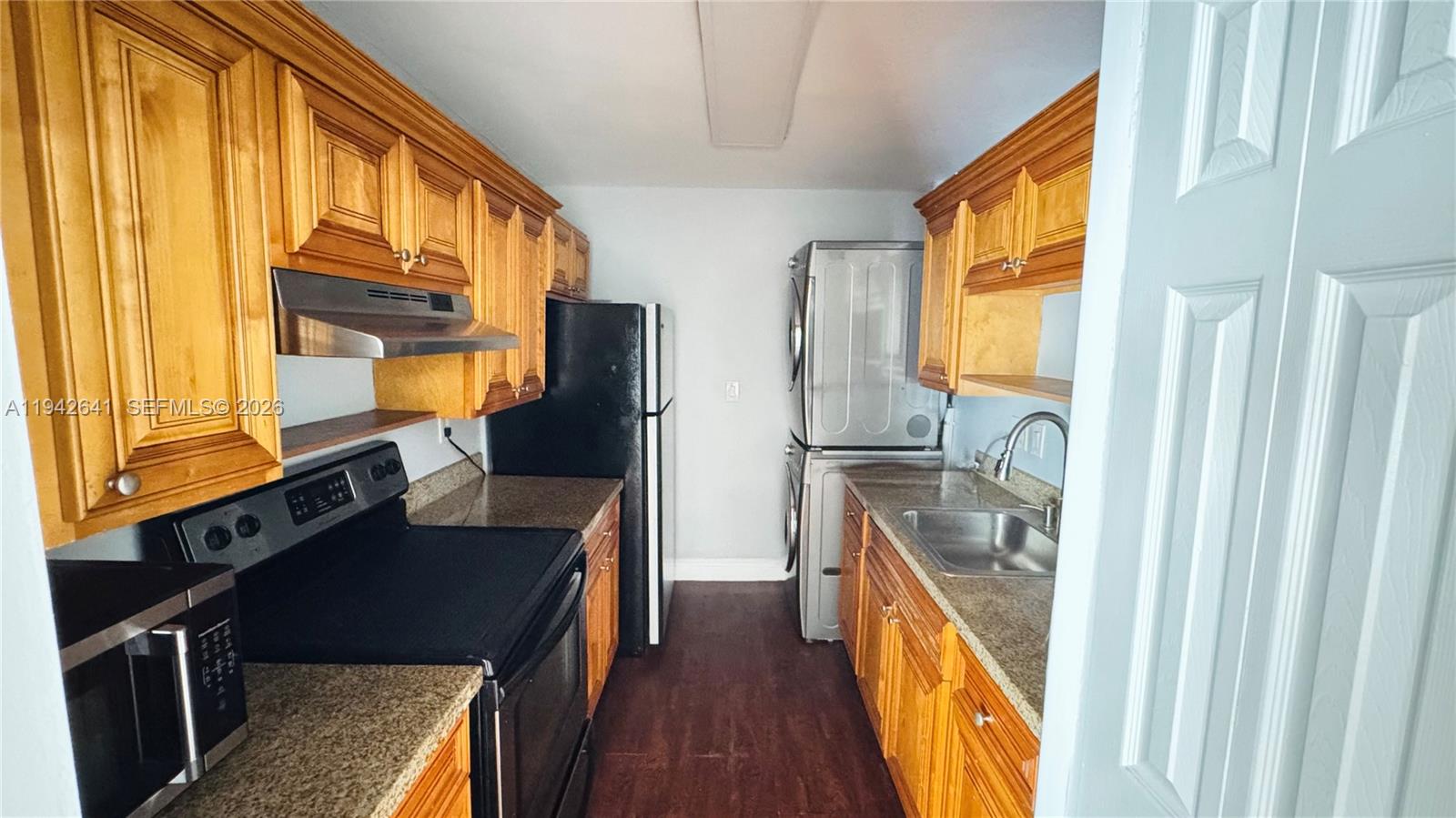 7226 Southwest 94th Place, Unit F7 Miami, FL 33173 - Photo 9 of 17 a kitchen with stainless steel appliances granite countertop a refrigerator a stove and a sink with wooden floor
