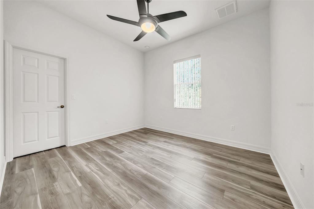 10177 Deer Street Spring Hill, FL 34608 - Photo 44 of 73 an empty room with wooden floor ceiling fan and windows