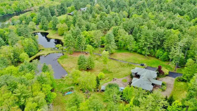 an aerial view of residential house with outdoor space and trees all around