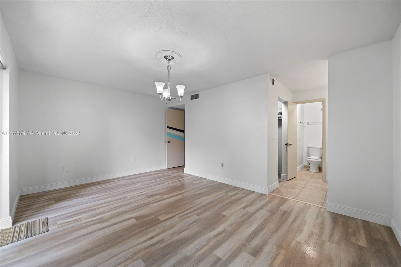 13298 Southwest 112th Terrace, Unit 461 Miami, FL 33186 - Photo 14 of 35 an empty room with wooden floor and chandelier