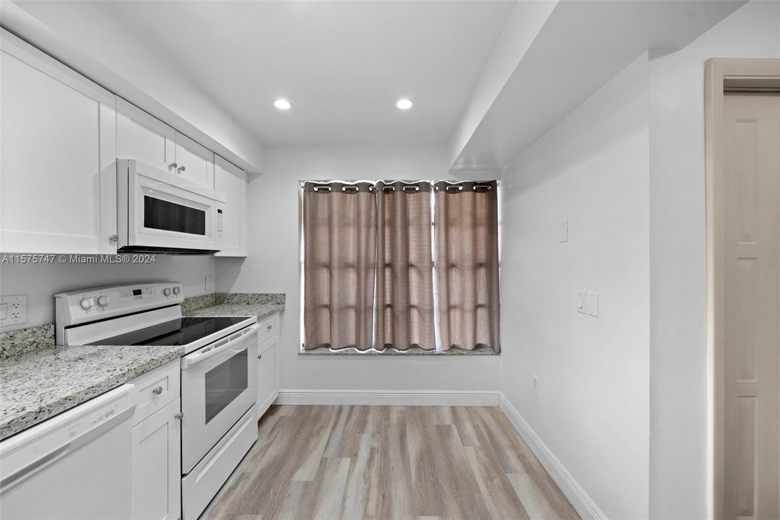 13298 Southwest 112th Terrace, Unit 461 Miami, FL 33186 - Photo 4 of 35 a kitchen with granite countertop a stove a sink and a microwave