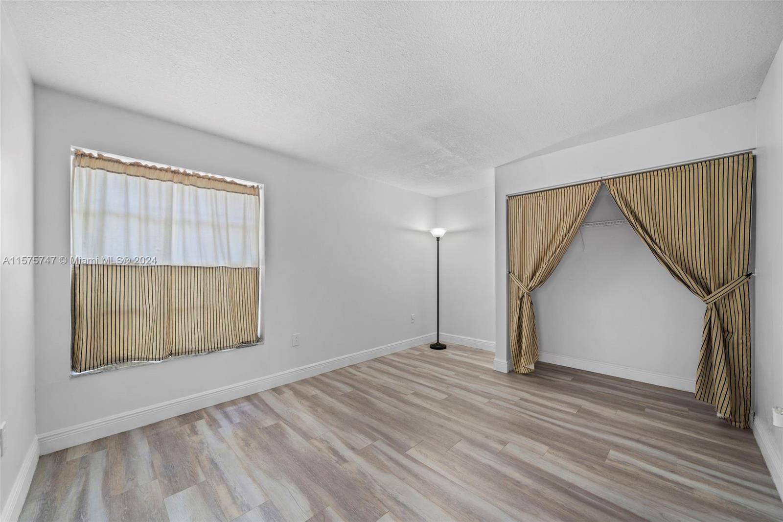 13298 Southwest 112th Terrace, Unit 461 Miami, FL 33186 - Photo 8 of 35 an empty room with wooden floor and windows