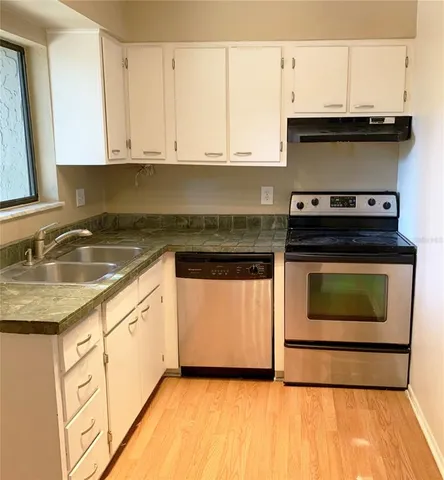 a kitchen with granite countertop a stove top oven microwave and cabinets