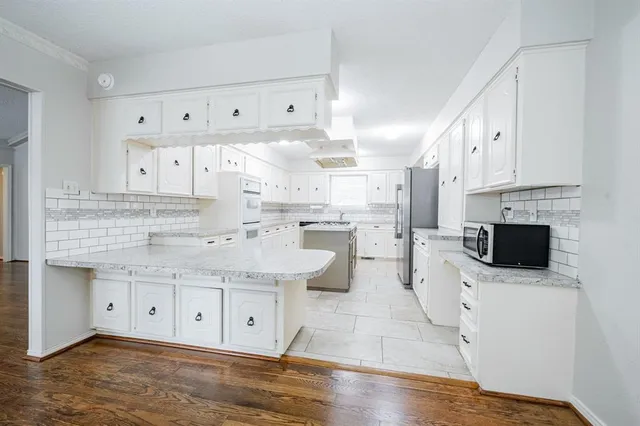 a view of a kitchen with kitchen island stainless steel appliances stove a refrigerator and a wooden floor