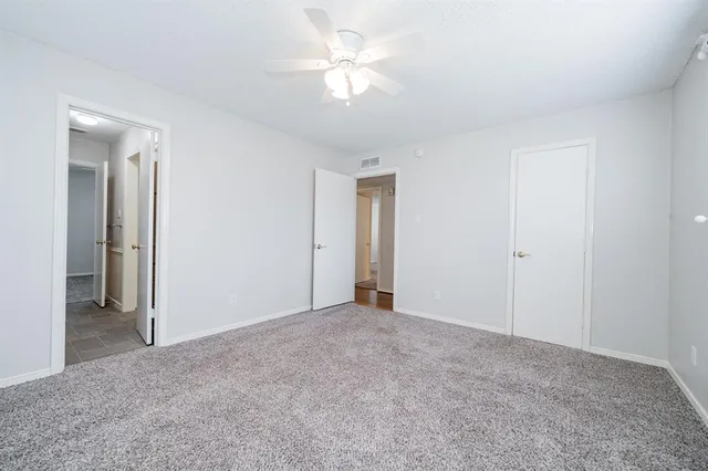 an empty room with windows and chandelier fan