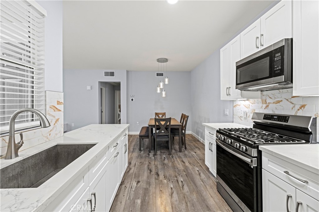 20000 Plum Canyon Road, Unit 1326 Saugus, CA 91350 - Photo 17 of 39 a kitchen with granite countertop a sink a stove top oven and cabinetry