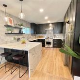 a kitchen with stainless steel appliances kitchen island granite countertop a sink a stove and a wooden floors