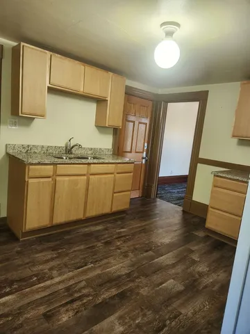 a view of a kitchen with a sink wooden cabinets and entryway