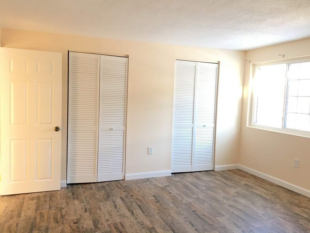 388 Great Road, Unit B14 Acton, MA 01720 - Photo 6 of 14 an empty room with wooden floor and windows with curtains