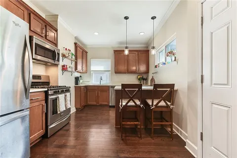 a kitchen with stainless steel appliances a table chairs refrigerator and microwave