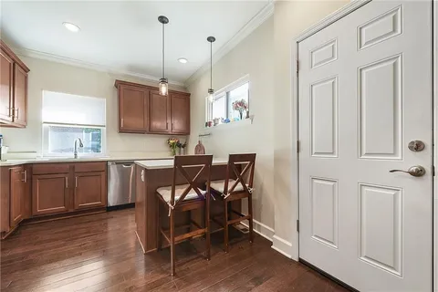 a kitchen with stainless steel appliances granite countertop a refrigerator a sink dishwasher a stove and white cabinets with wooden floor